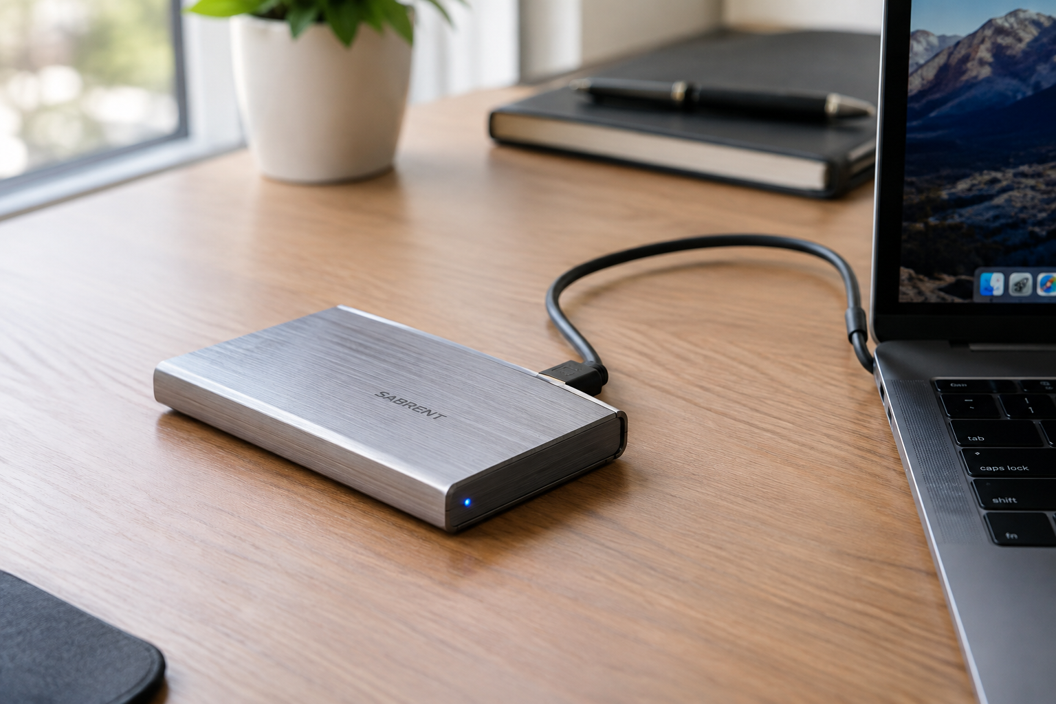 External NVMe SSD enclosure connected to a laptop via USB-C cable on a desk