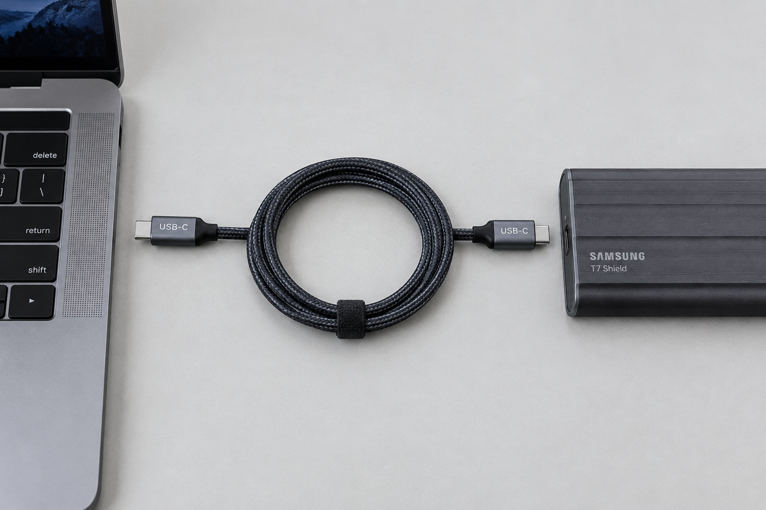 USB-C cable connecting a laptop port to an external SSD enclosure, illustrating the data connection chain